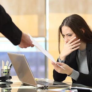Woman distressed as her employer points at a document, symbolizing wrongful termination concerns.