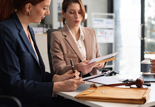 Women lawyers working together on a case, signing papers in a law office.
